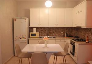 a kitchen with white cabinets and a white table and chairs at Άνετο και όμορφο διαμέρισμα in Xanthi