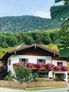 une maison avec des fleurs sur ses balcons dans l'établissement Sehr schöne Ferienwohnung in ruhiger jedoch zentraler Lage mit freiem Blick auf unsere Berge, à Schneizlreuth
