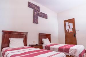 a room with two beds and a cross on the wall at Hotel Don Nino in Oaxaca City