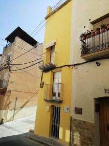 Un bâtiment jaune avec balcon et fenêtres donne sur une rue. dans l'établissement Traditional Spanish Town House, à Móra d'Ebre
