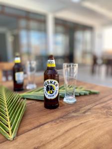 una bottiglia di birra su un tavolo di legno con un bicchiere di YU Resort a Msambweni