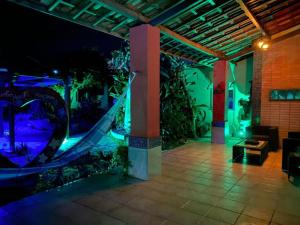 een patio met een hangmat en 's nachts een tuin bij Pousada Villa Flamboyant in Beberibe