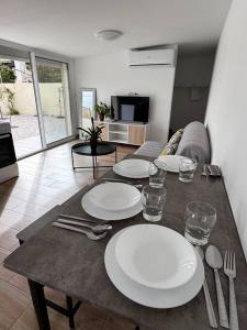 a table with plates and silverware on it in a living room at Maison entièrement Neuve in Marseille