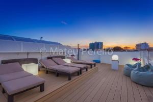 a rooftop deck with couches and chairs on a roof at Ferienwohnung in Son Baulo mit Grill in Can Picafort