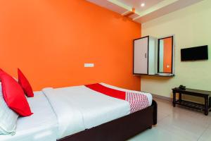 - une chambre avec des murs orange et un lit avec des oreillers rouges dans l'établissement OYO Sindhura Guest House, à Raspari Palao