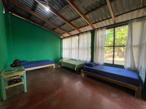 Habitación con 2 camas y pared verde. en Sugarloaf Beach House & Surf Lodge, en El Cuco