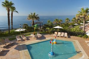a swimming pool with chairs and the ocean in the background at Elba Estepona Gran Hotel & Thalasso Spa in Estepona