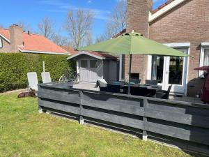 a deck with a green umbrella and chairs on a house at Ferienhaus CARPE DIEM Schoneveld - Breskens - Urlaub mit Hund in Breskens