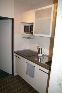 eine kleine Küche mit weißen Schränken und einer Mikrowelle in der Unterkunft Fehmarn Sonne Meer in Burgtiefe auf Fehmarn 