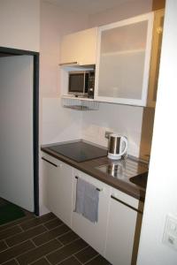 a small kitchen with white cabinets and a microwave at Fehmarn-Sonne-Meer in Burgtiefe auf Fehmarn  +25 photos