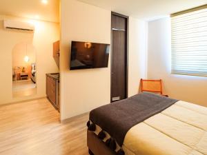 a bedroom with a bed and a flat screen tv at Tribu Sonata with pool in Guadalajara
