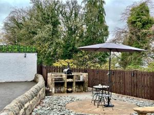 a patio with a table and an umbrella at Gleddoch Coach House in Langbank