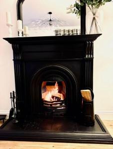 a black fireplace with a fire in it at Gleddoch Coach House in Langbank