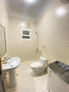La salle de bains blanche est pourvue de toilettes et d'un lavabo. dans l'établissement نايتس للوحدات المفروشة, à Tabuk