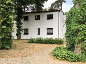 a white house with black windows and a brick driveway at Vienības Family. in Jūrmala