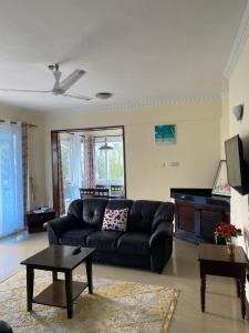 a living room with a black couch and a table at Ocean Blue Retreat-3 minute walk to Nyali Center and 3 minute walk to the Beach in Mombasa
