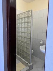 a bathroom with a toilet and a glass shower door at Ocean Blue Retreat-3 minute walk to Nyali Center and 3 minute walk to the Beach in Mombasa