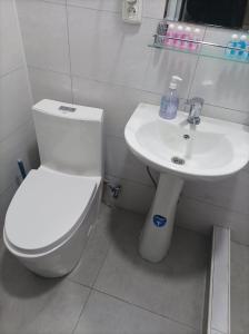 a bathroom with a white toilet and a sink at Nice Trip in Yunusobod