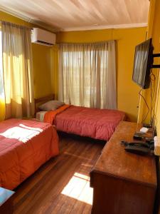 Habitación de hotel con 2 camas y TV en Hostal Radal Molina, en Molina
