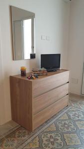 een tv op een dressoir met een spiegel bij Il terrazzo sul porto in Sciacca