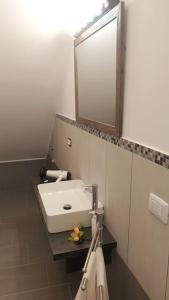 een badkamer met een witte wastafel en een spiegel bij Il terrazzo sul porto in Sciacca