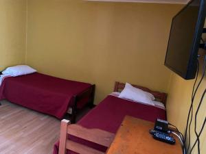 Habitación con 2 camas, TV y mesa. en Hostal Radal Molina, en Molina