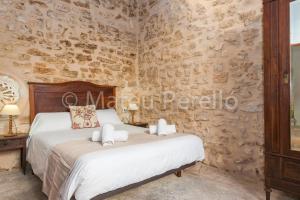une chambre avec un lit et un mur en pierre dans l'établissement Ferienhaus in Santa Margalida mit Kleinem Pool, à Santa Margalida