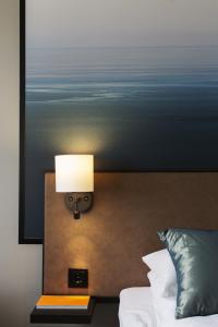 a bedroom with a bed and a lamp on the wall at Quality Hotel Grand Kristiansund in Kristiansund