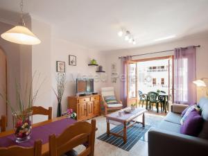 ein Wohnzimmer mit Sofa und Tisch in der Unterkunft Charmante Wohnung in Son Baulo mit Grill in Can Picafort