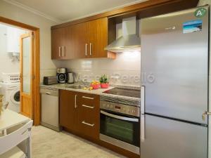 eine Küche mit Küchengeräten aus Edelstahl und Holzschränken in der Unterkunft Charmante Wohnung in Son Baulo mit Grill in Can Picafort + 14 Fotos