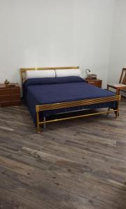 a bedroom with a bed with blue sheets and wood floors at B&BEES in Rocca Ranieri