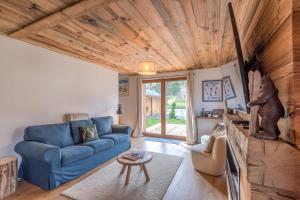 a living room with a blue couch and a wooden ceiling at Magnificent chalet with view in Praz-sur-Arly - Welkeys in Praz-sur-Arly