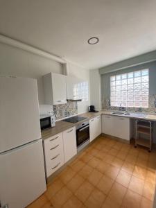 a large kitchen with white cabinets and a tile floor at Apartamento ideal para familias in Móra la Nova