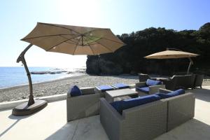 Beach Terrace Kushimoto - Vacation STAY 37415v في Wabuka: مجموعة من الكراسي ومظلة على الشاطئ