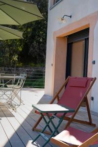 a chair and an umbrella on a porch at Appartement T3 bas de Villa in Vero
