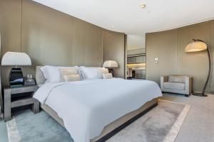 a bedroom with a large white bed and a chair at Burj Khalifa, Armani hotel 1 bedroom apartment in Dubai