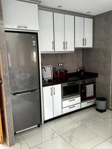 kuchnia z białymi szafkami i lodówką ze stali nierdzewnej w obiekcie Riad Jad - Sweet Duplex Appartement w Marakeszu