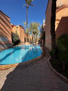 une piscine bordée de palmiers et un bâtiment dans l'établissement Riad Jad - Sweet Duplex Appartement, à Marrakech