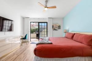 a bedroom with a red bed and a ceiling fan at Desert Rose- Condo with Pool and Tennis Courts in Palm Springs +49 photos