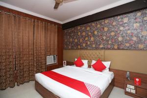 OYO Hotel K-town في Gharaunda: غرفة نوم بسرير كبير ومخدات حمراء