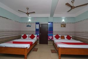 Cette chambre comprend 3 lits avec des oreillers rouges. dans l'établissement OYO Prantika Banquet, à Digha