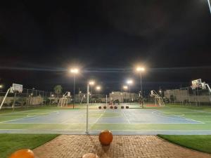 a tennis court at night with lights on it at Cozy family home in private condo in Santa Cruz de la Sierra