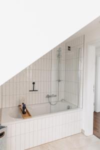 a bath tub with a shower in a white bathroom at Vogelnest - Gemütlich und klimatisiert - Perfekt zum Abschalten! in Nordheim