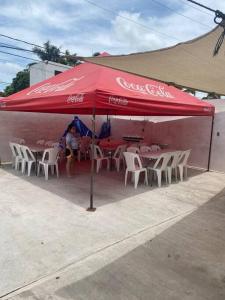una sombrilla de cocacola con mesas y sillas frente a un edificio en Casa con alberca privado cómoda, en Tampico