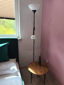 a room with a table and a lamp next to a bed at Apartament Przebiśnieg in Polanica-Zdrój