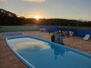 a swimming pool with a sunset in the background at Hotel Fazenda Recanto do Monte Alegre in Piraju