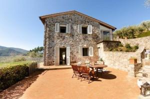 een stenen huis met een tafel en stoelen op een patio bij Ferienhaus mit Privatpool für 7 Personen ca 200 qm in Capannori, Toskana Provinz Lucca in Capannori