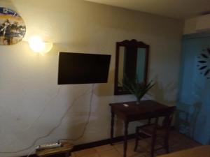 a television on a wall in a room with a table at studio francelu in Sainte-Anne