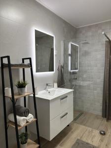 uma casa de banho branca com um lavatório e um chuveiro em Apartman ZEN em Popovača