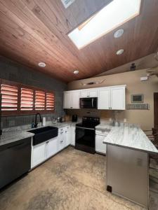 a large kitchen with white cabinets and black appliances at Rustic Retreat New Cabin on 2 Acres Fully Fenced! Summer special 2 complimentary tickets to Bearizona offer expires July 31st 2024 in Williams